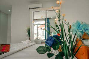 Ett modernt hotellrum med en stor säng, en krukväxt och utsikt över staden genom fönstret.