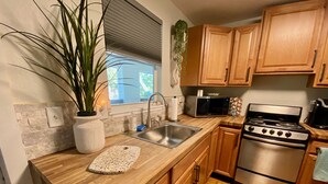 Una cocina con armarios de madera, un lavamanos de acero inoxidable, un microondas y una estufa.