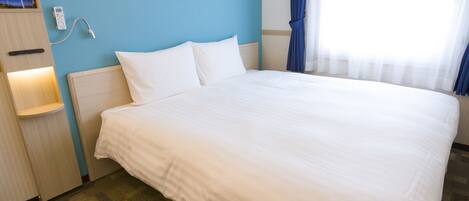 A hotel room with a large bed, a nightstand, a wall clock, and a window with curtains.