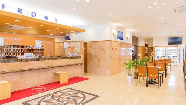 A hotel reception area with a counter, seating area, and a large decorative floor design. - Toyoko Inn Joetsumyoko-eki Nishi-guchi (Joetsu)
