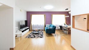 Ein modernes Wohnzimmer mit Fernseher, Sofa und Essbereich.