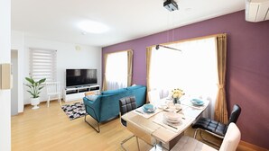 Ein modernes Wohnzimmer mit einer Couch, einem Fernseher, einem Esstisch und Stühlen.