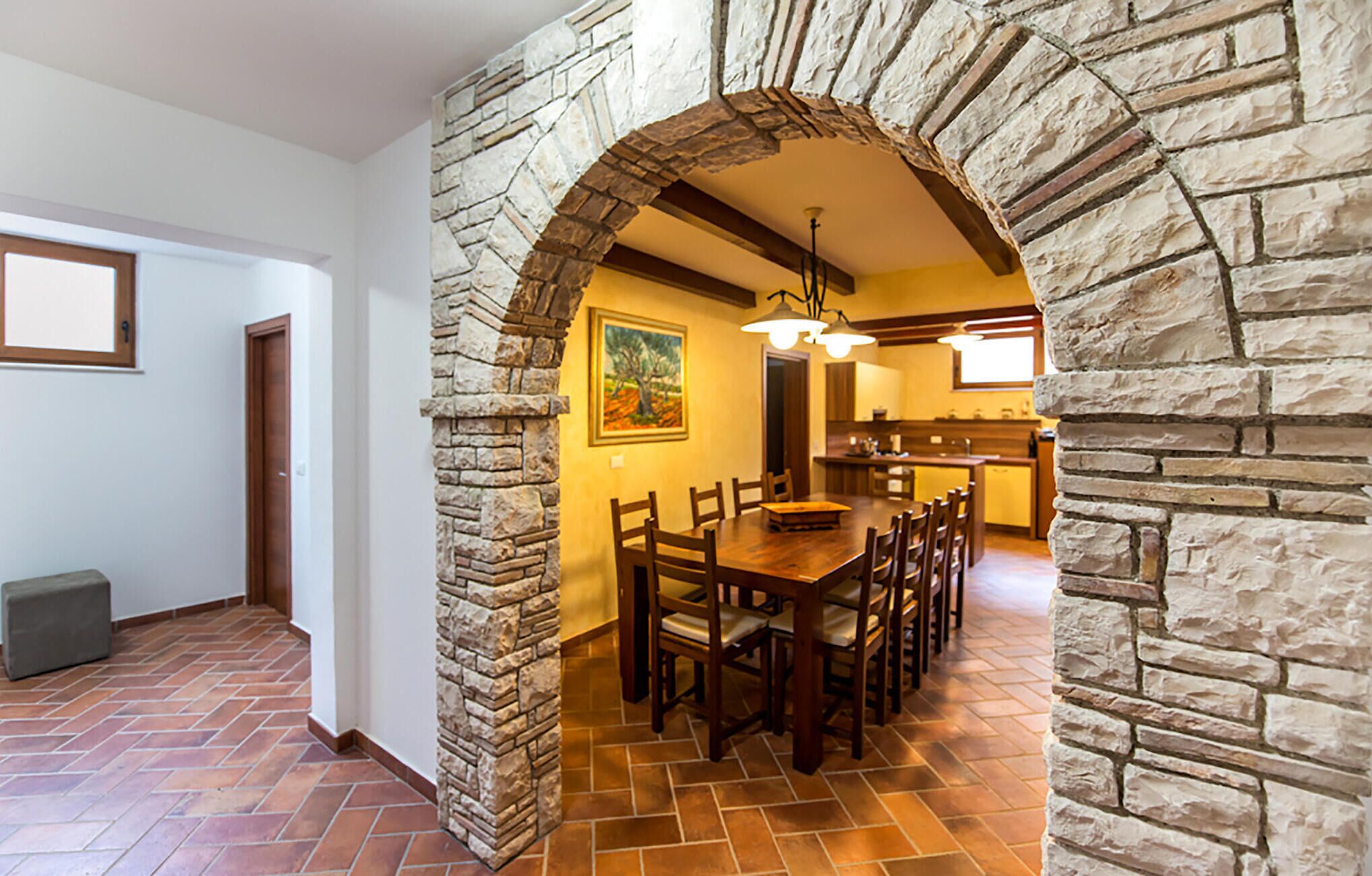 Un espace repas agrémenté d’une arche en pierre, d’une table en bois et de chaises.
