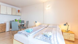 Une chambre comprenant un lit, des tables de chevet, un bureau avec une chaise et une petite kitchenette.