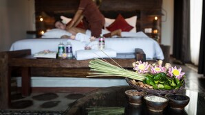 Une salle de spa équipée d’un lit, d’une table de massage et d’une table ornée d’un arrangement floral et de diverses bouteilles.