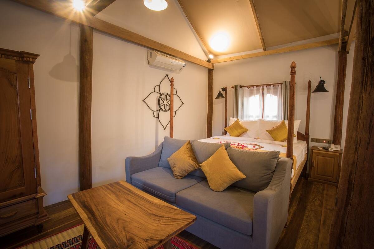 Une chambre à coucher avec un lit, une armoire en bois, un canapé et une petite table.