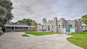Una propiedad residencial con garaje, un patio cubierto y un edificio de piedra con puerta azul.