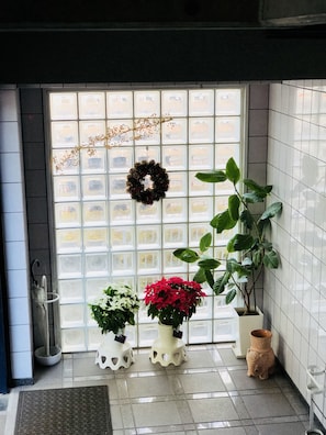 A door with a frosted glass panel, a wreath, and three potted plants. - FC House Shibuya No.1 (Tokyo)