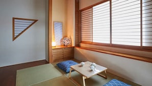 A traditional Japanese room with tatami flooring, a low table with tea set, a cushion, and a shoji screen window. - FC House Shibuya No.1 (Tokyo)