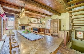 Enjoy cooking in this kitchen with a large island, sink, and stove, surrounded by exposed beams and a stone fireplace.