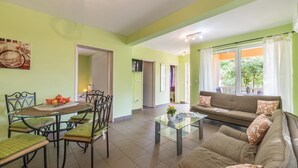 A spacious living area with a dining table, chairs, a sofa, and a coffee table.