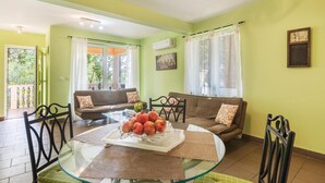 A living room with a glass dining table, two sofas, and a balcony.