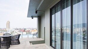 Un balcon avec une table et des chaises, de grandes fenêtres et une vue sur la ville.