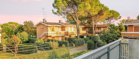 Un barrio residencial con casas, un árbol grande y una cerca de metal.