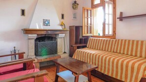 A living room with a fireplace, a sofa, a table, and a window.