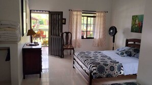 A bedroom with a bed, a chair, a desk with a lamp, a window with curtains, and a fan. - Finca Campestre J&J (Quimbaya)