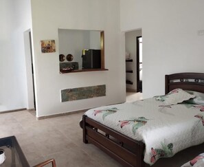 A bedroom with a bed, a mirror, a shelf with decorative items, and a stone accent wall. - Finca Campestre J&J (Quimbaya)