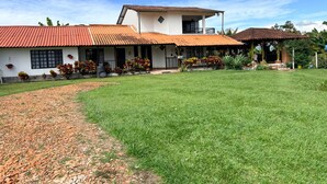 A two-story house with a covered patio, a well-maintained lawn, and a clear sky. - Finca Campestre J&J (Quimbaya)