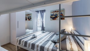 Un dormitorio moderno con literas, ropa de cama a rayas y decoración temática náutica.