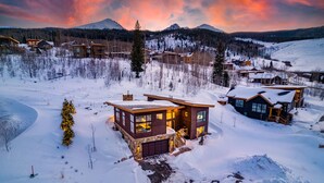 Eine moderne Lodge mit Natursteinfassade, großen Fenstern und einer Holzterrasse.