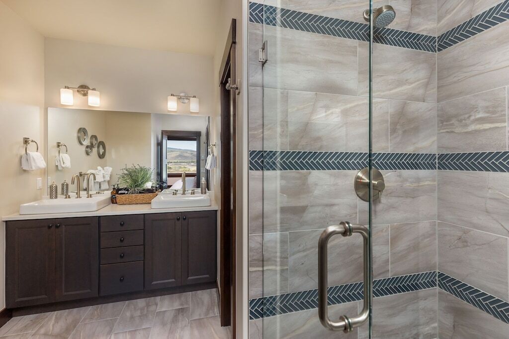 A modern bathroom with two sinks, a mirror, and a shower with a glass door.