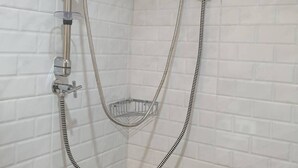 A shower with a handheld showerhead, a wall-mounted faucet, and a handheld shower hose.