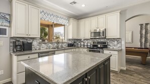 Una cocina moderna con armarios blancos, una isla grande y un salpicadero de baldosas grises.