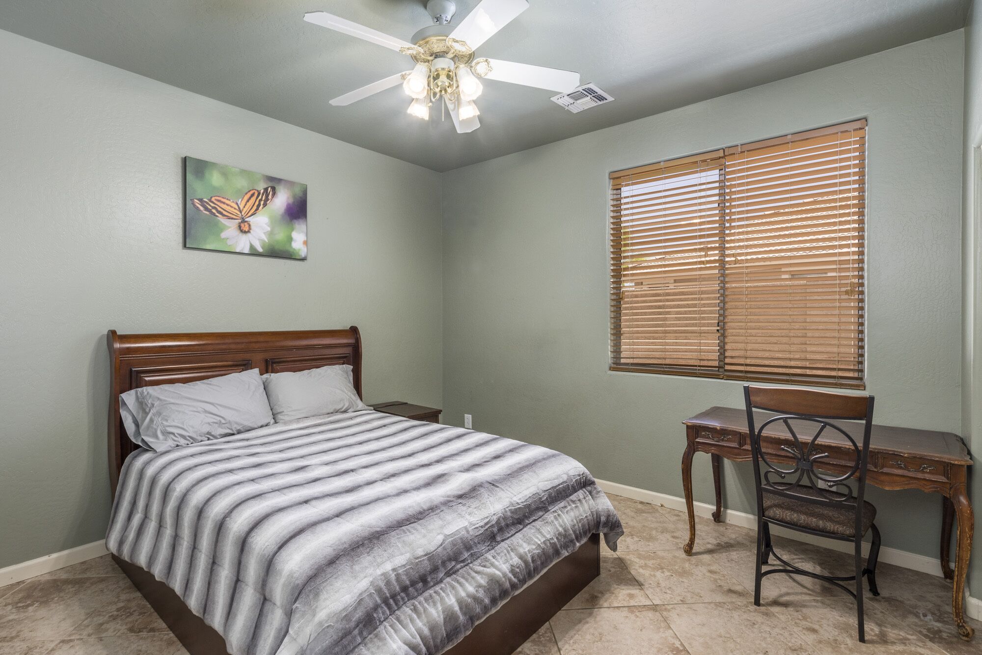 A bedroom with a bed, a desk, and a chair.