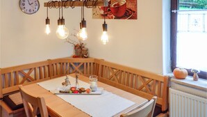 Un'accogliente sala da pranzo con una panca in legno, un tavolo con sottopiatti e un orologio a muro.