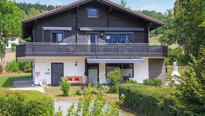 Una casa a due piani con un balcone, un piccolo garage annesso e un giardino curato.