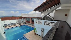 A rooftop swimming pool with a view of the sea, a covered staircase, and a sign with Chinese characters. - Bay Inn (Tirukalukundram)