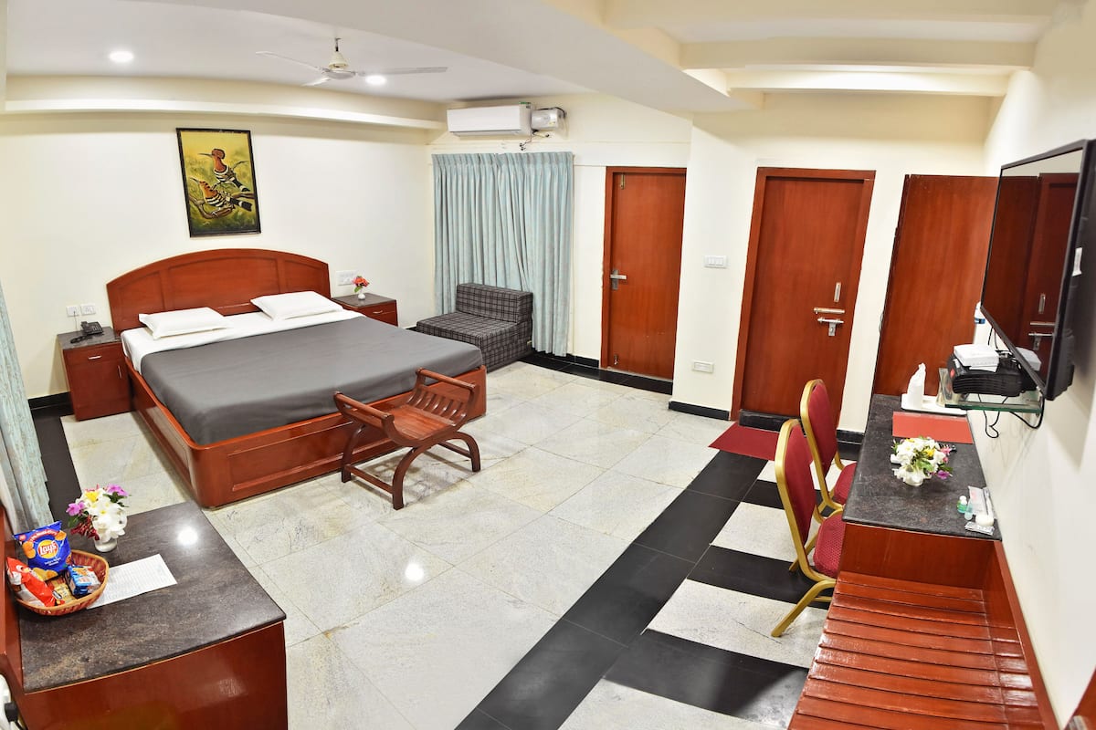 A hotel room with a bed, a desk, a chair, a wardrobe, and a bathroom.