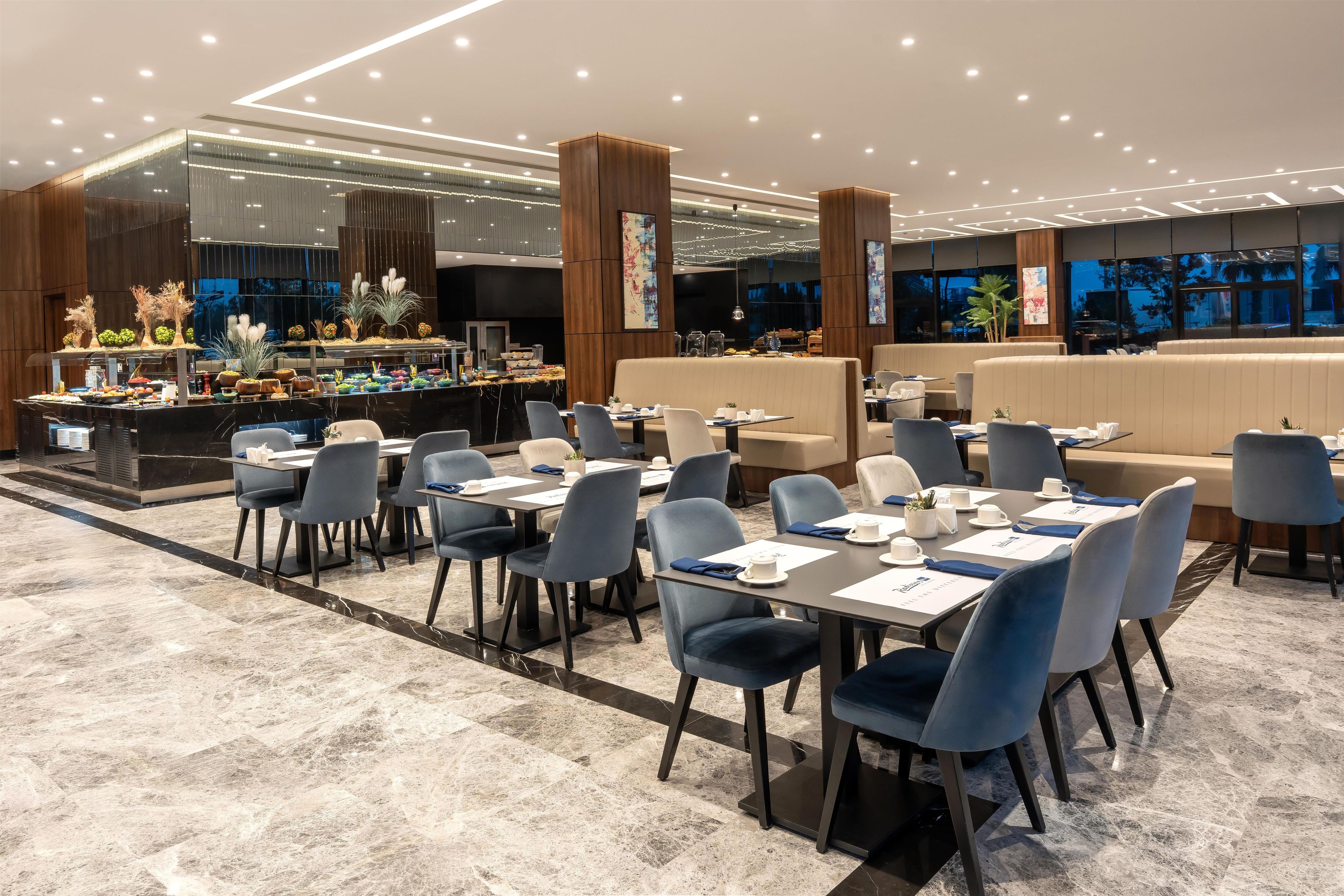 Un restaurante moderno con bufé, zona de estar y vistas panorámicas de la ciudad.