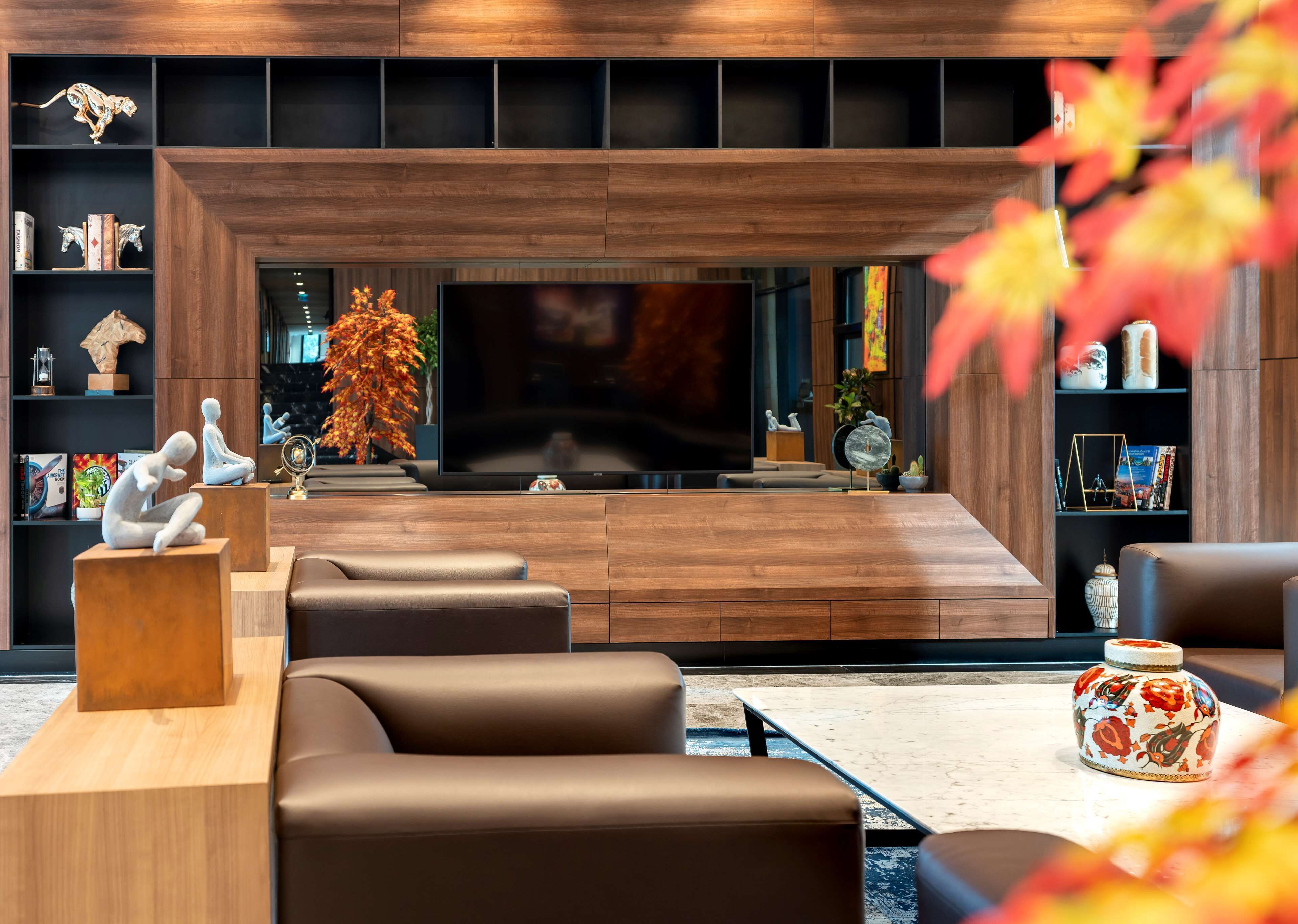A modern living room with a large flat-screen TV, leather sofas, and a wooden entertainment unit with various decorative items.