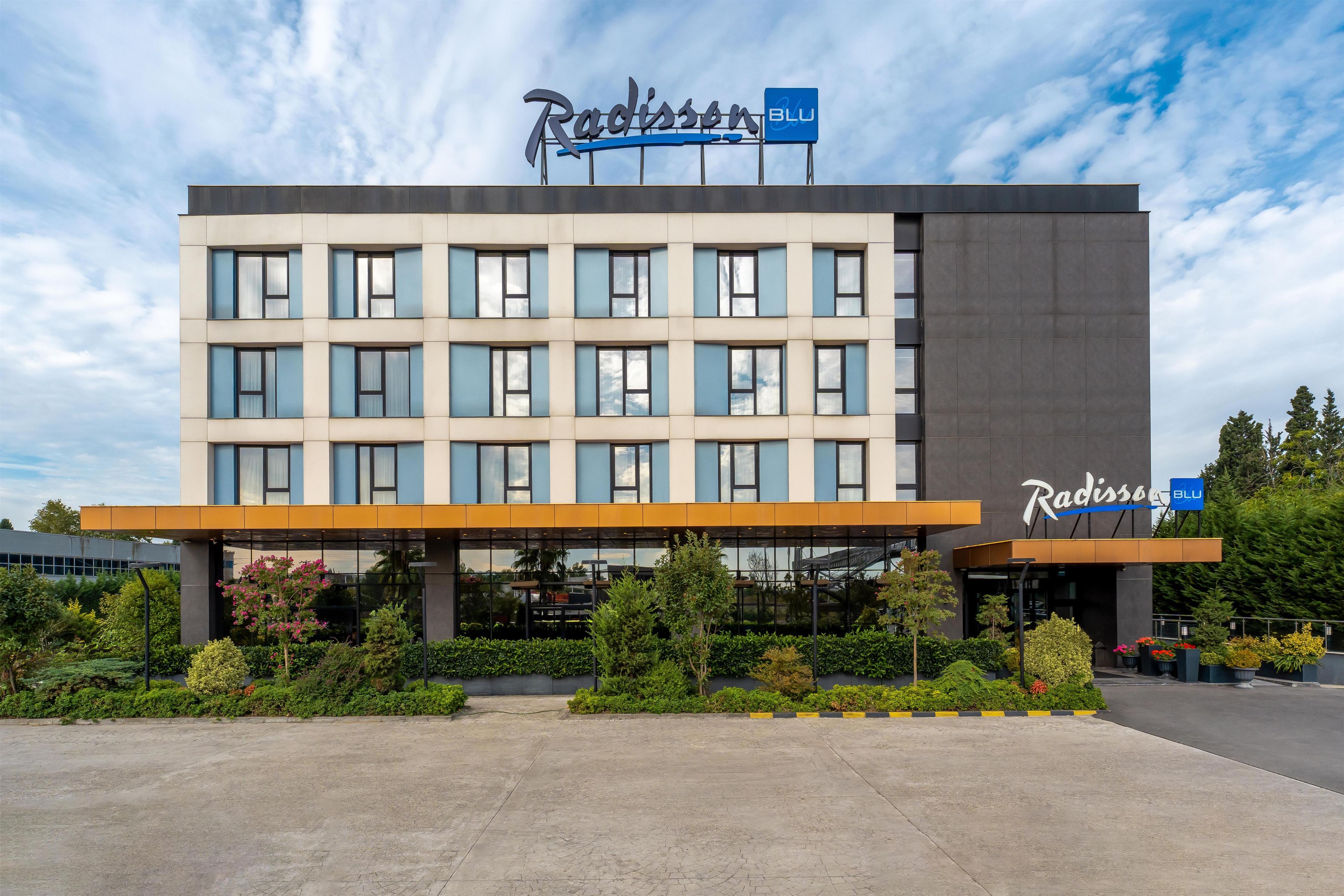 Et Radisson Blu hotel med en moderne facade, mange vinduer og et anlagt indgangsområde.