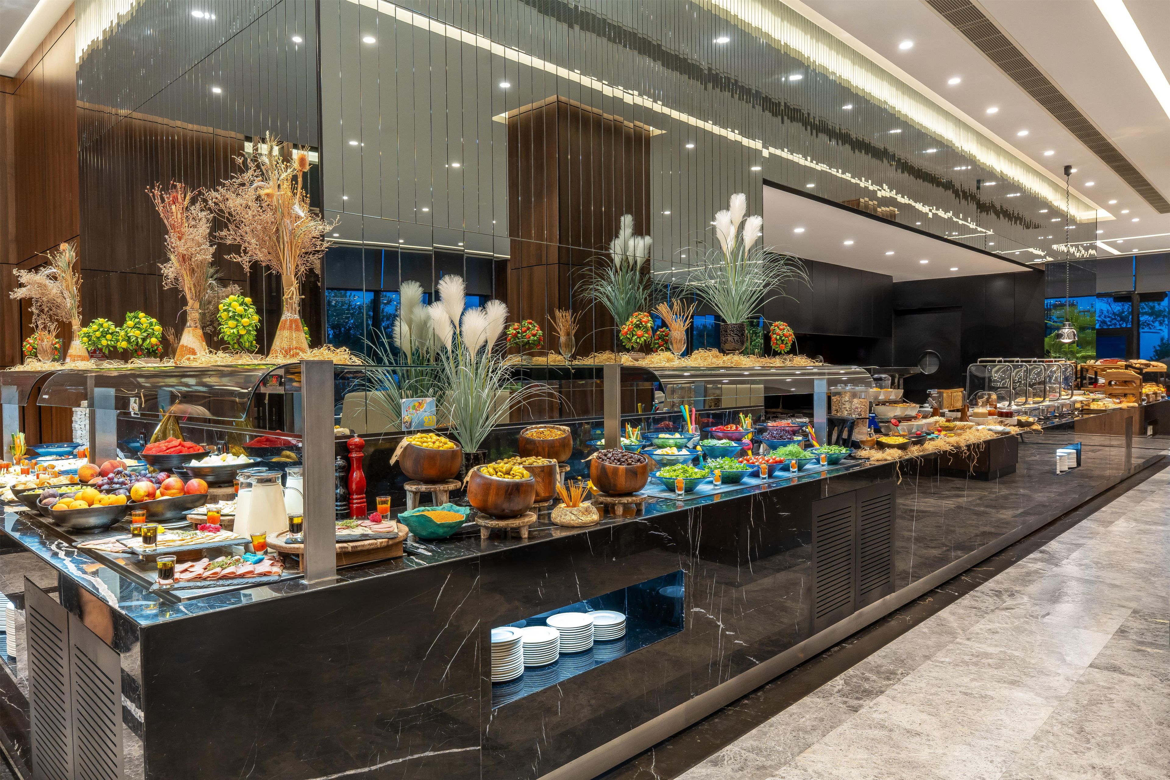 A buffet area with various food items and decorative plants.