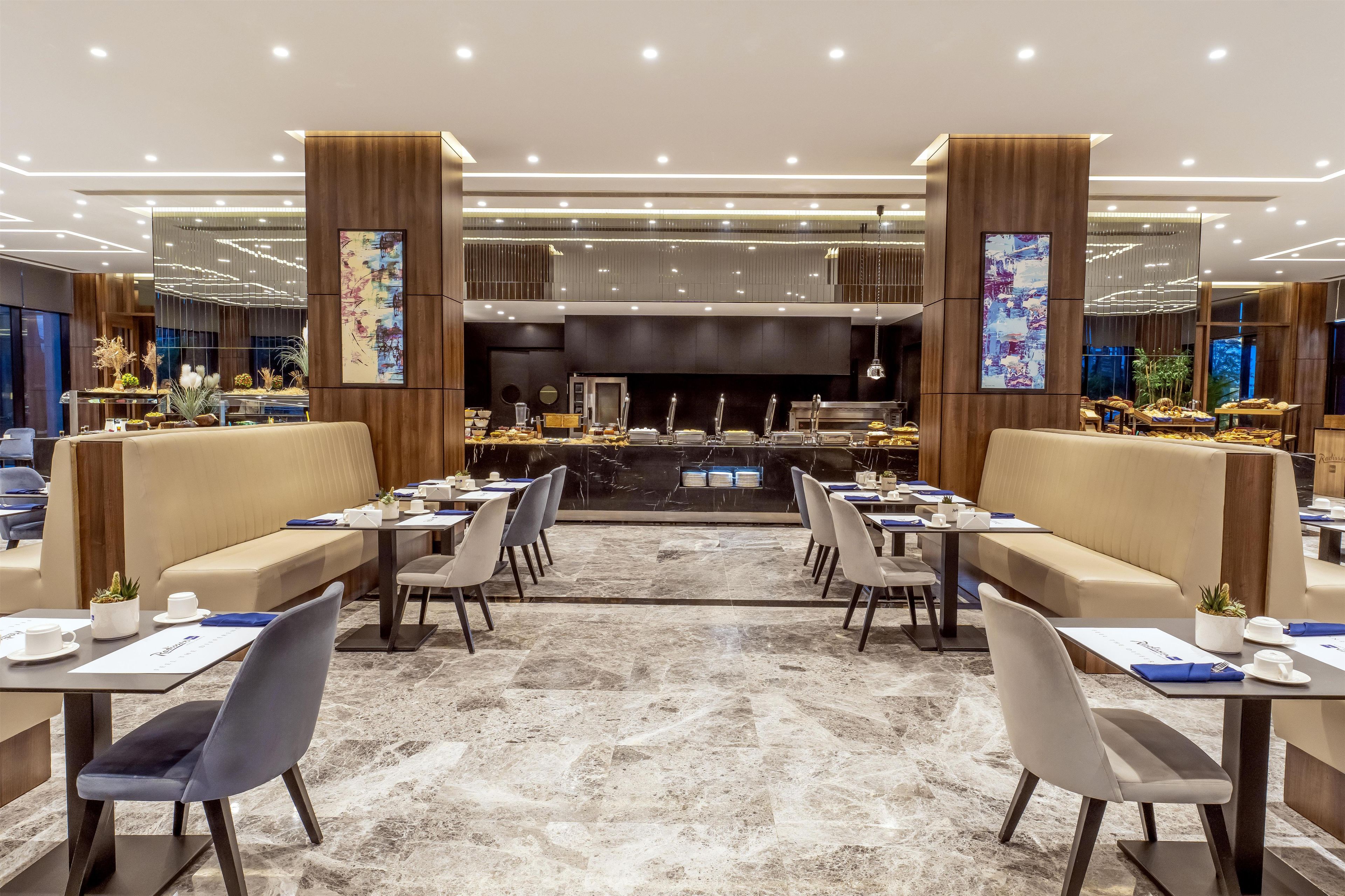 A modern restaurant with high tables and booths, a marble floor, and artwork on the walls.