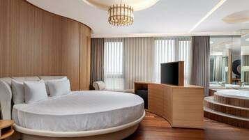Un dormitorio moderno con una cama grande, un televisor y un tocador de madera con espejo.