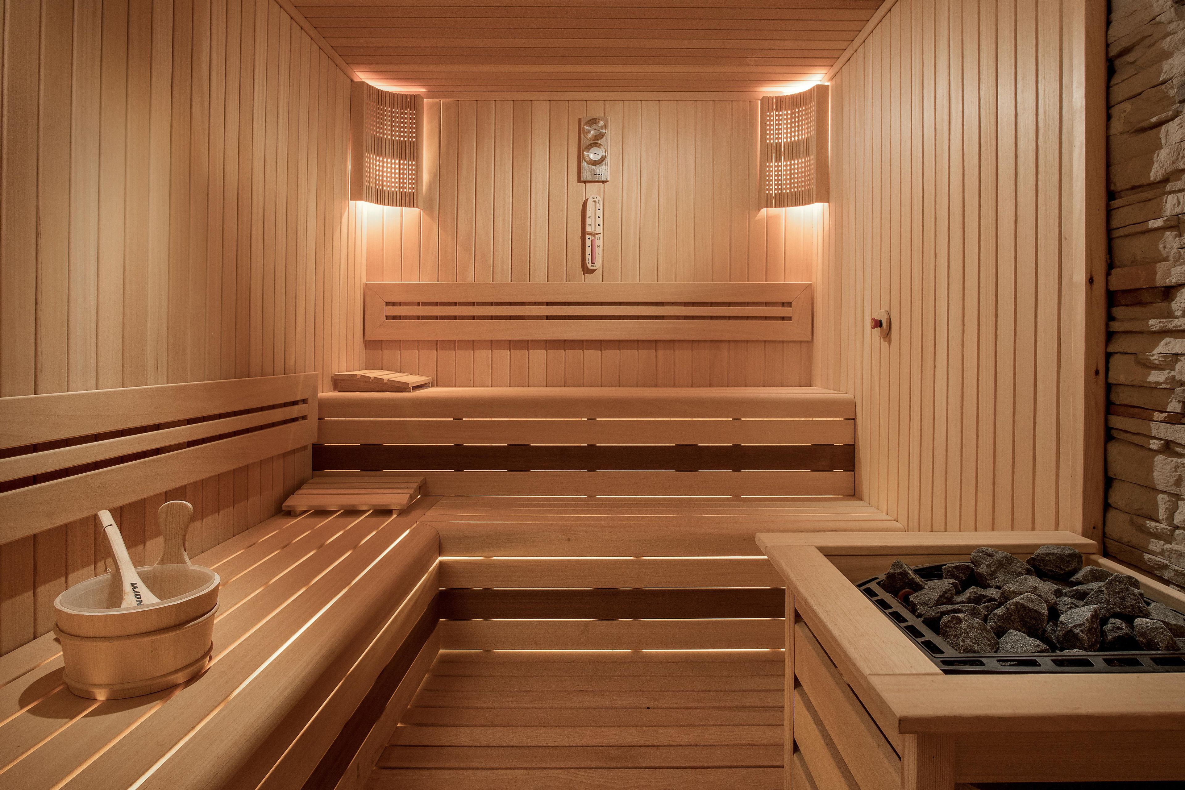 Una sauna con bancos de madera, un calentador en la pared y una pared de piedra.