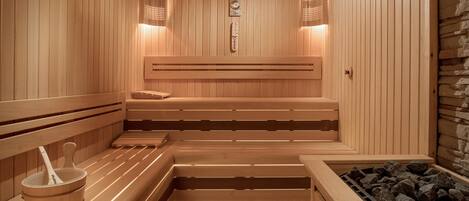 Un sauna avec des bancs en bois, un radiateur fixé au mur et un mur en pierre.