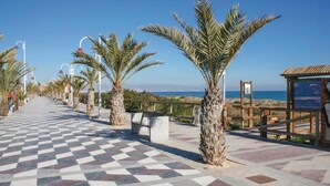 Un vialetto lastricato con palme, un pavimento a scacchi e vista sul mare.