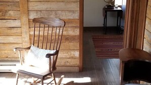 Una habitación rústica con paredes de madera, un sillón mecedor, una mesita con un globo terráqueo y un cuadro de un paisaje nevado.