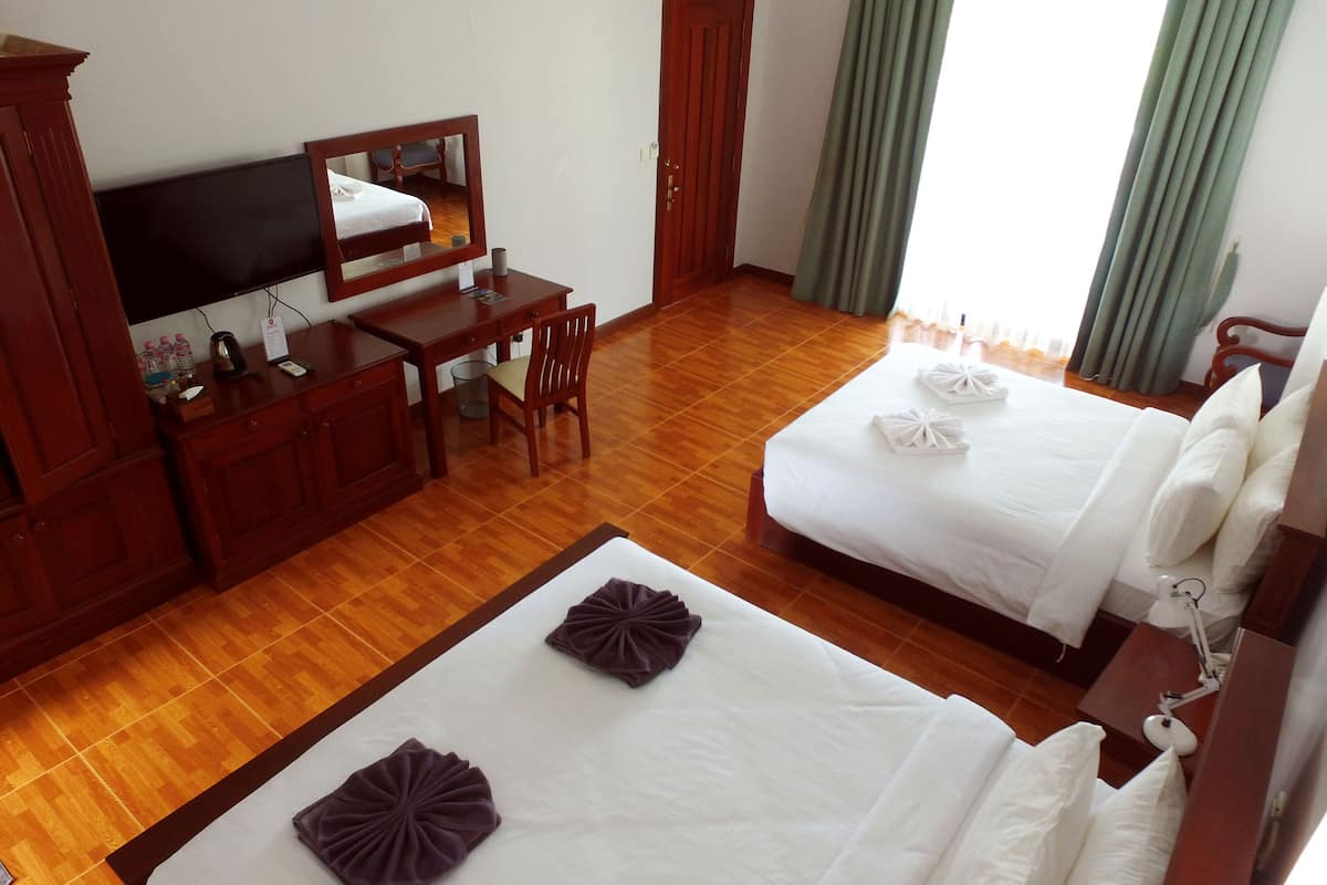 A hotel room with a wooden desk, a television, a bed with white bedding, and a large mirror.