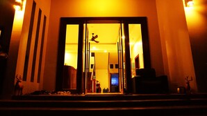 L’entrée d’un hôtel, avec une grande porte vitrée, un ventilateur de plafond et un escalier menant à l’intérieur.