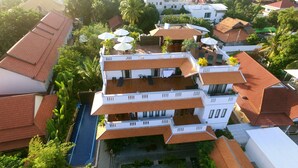 Un immeuble à plusieurs étages doté d’une piscine, de nombreux balcons et de parasols d’extérieur.