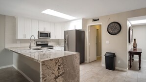 A modern kitchen with white cabinets, a granite island, stainless steel appliances, and a clock on the wall. - Beautiful CLEAN Townhome in East Mesa -  w/Community Heated Pool (Mesa)