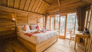 A wooden room with a bed, a table, and a view of the outside. - Pi Karya Beach (Penida Island)
