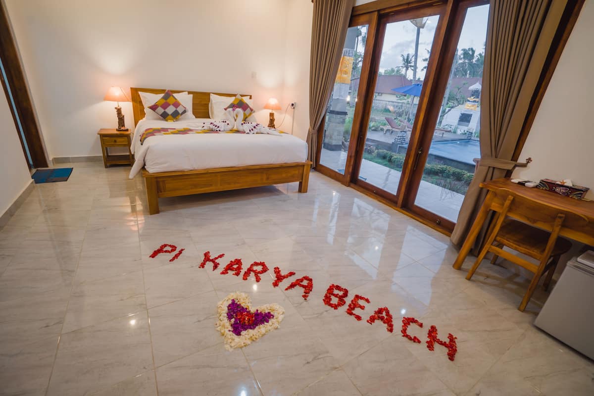 A bedroom with a bed, a nightstand, a desk, and a view of the beach.
