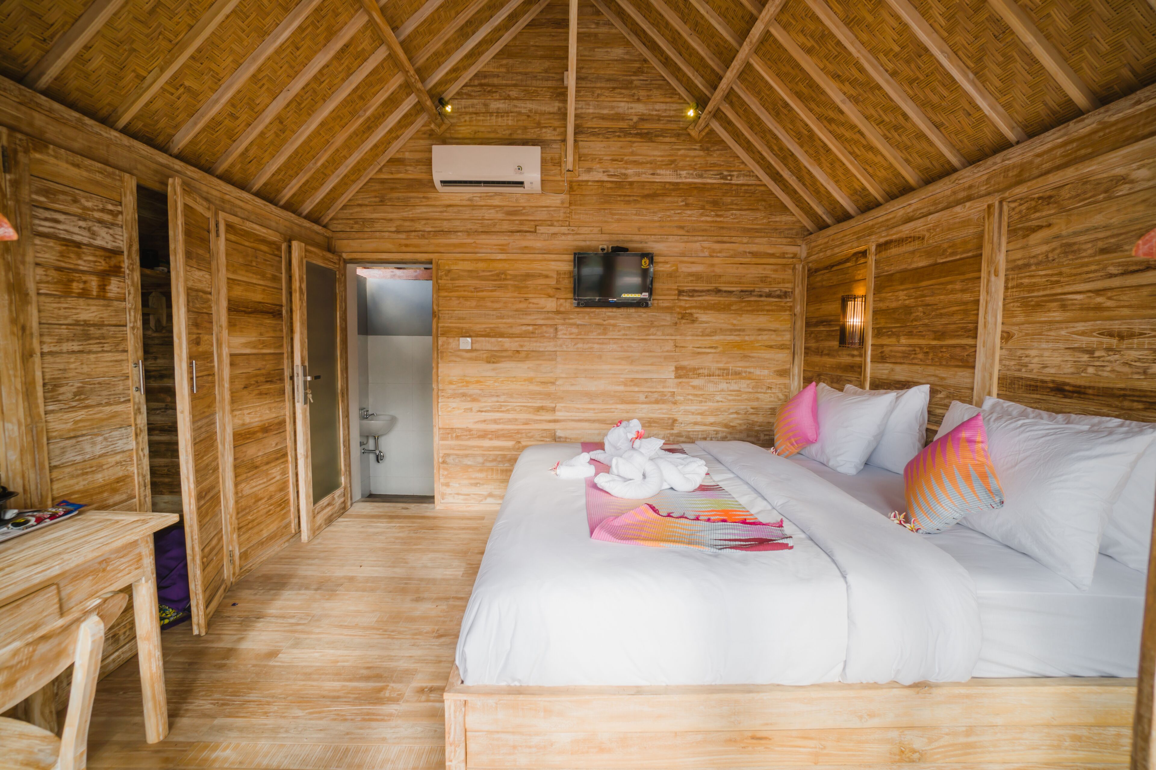 A wooden cabin with a bed, a desk, and a bathroom.