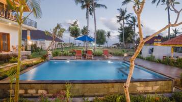 Una piscina al aire libre, sombrillas, sillones reclinables de piscina